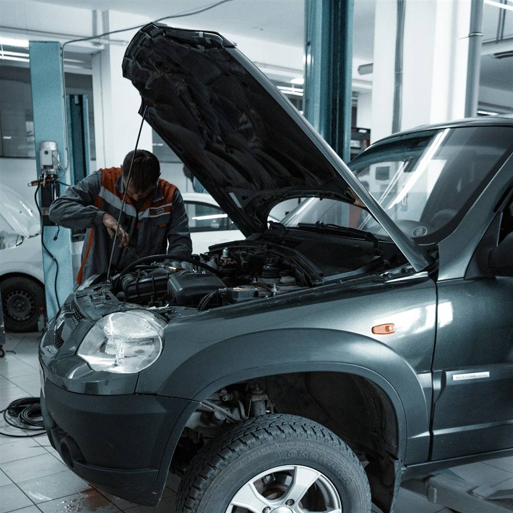 Technician working under the hood of a car in a clean dealership service bay